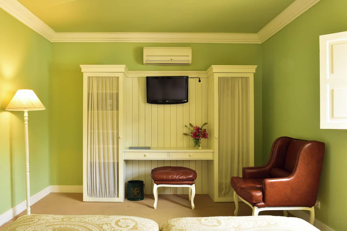 Una habitación con escritorio, televisión, silla, lámpara y cubo de basura.