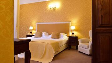 A hotel room with a large bed, two bedside tables with lamps, a chair, and a wooden wardrobe.