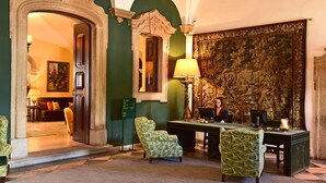 A lobby with a green wall, a large tapestry, and a desk with two chairs. - Pousada Convento de Evora - Historic Hotel (Évora)