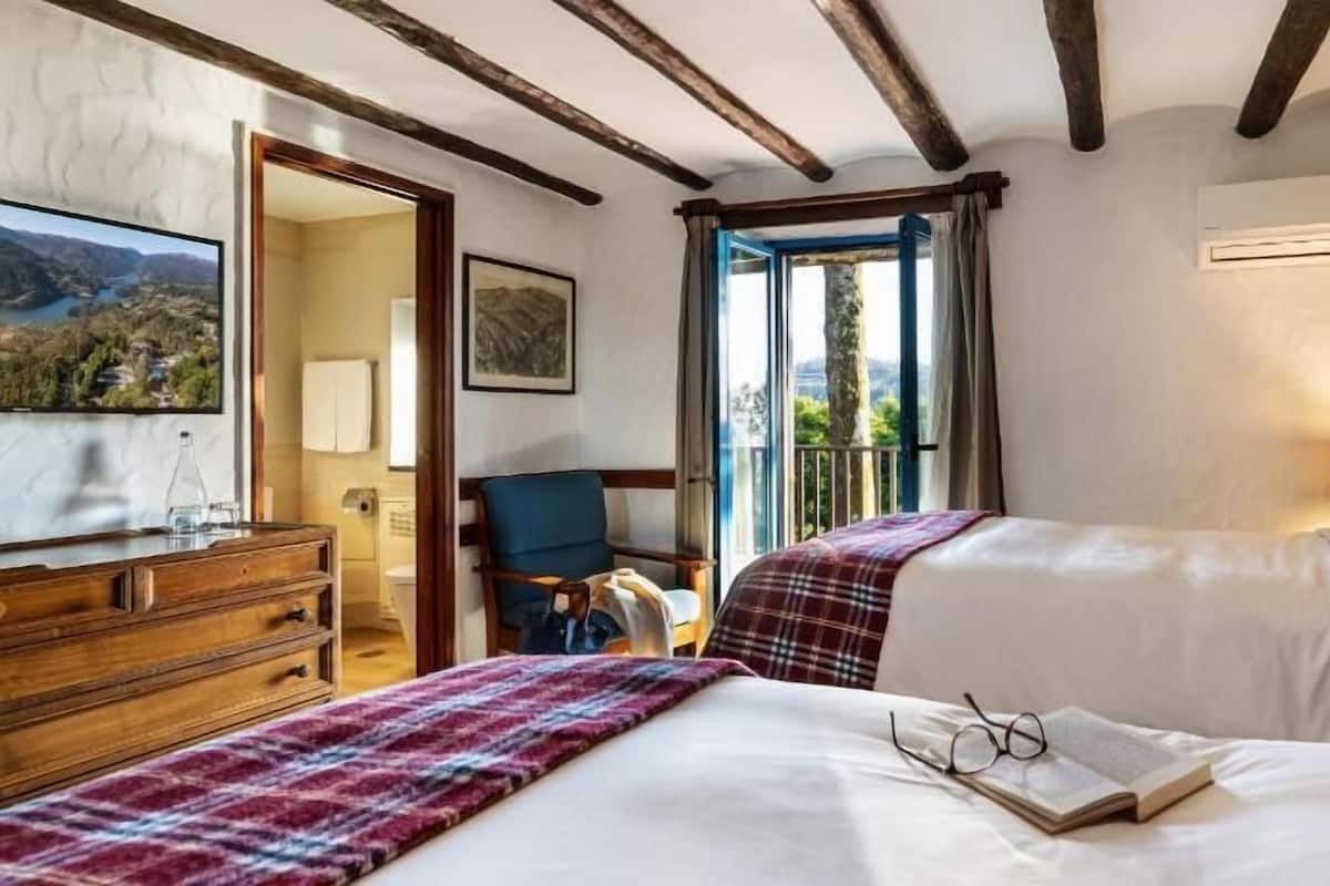 Een hotelkamer met een bed, een stoel, een bureau en een raam met uitzicht.