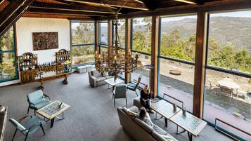 A spacious room with large windows, a chandelier, and a variety of seating options.