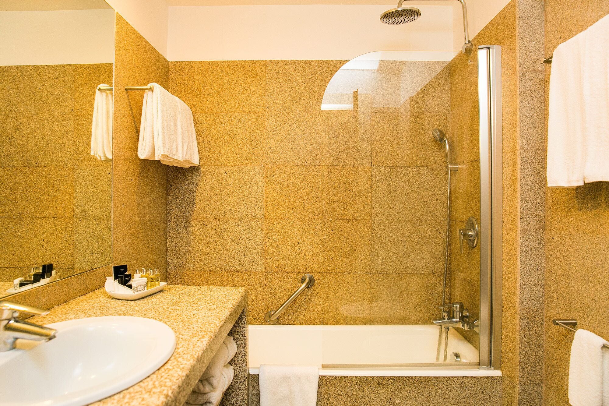 A modern bathroom with a glass-enclosed shower, a sink, and a vanity with a towel rack.