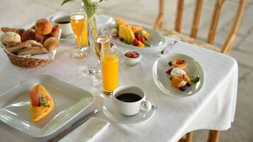 Mesa posta para o café da manhã, com diversos pratos, incluindo pães, frutas e bebidas.