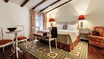 Een hotelkamer met een bed, twee nachtkastjes, een stoel, een kleine tafel met een schaal en een kamerbreed tapijt.
