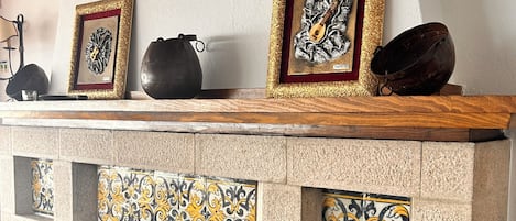 A fireplace with decorative tiles, a coat of arms, and framed artwork on the mantel.