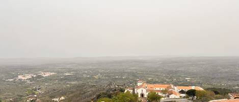 A panoramic view of a town with terracotta-roofed buildings and a distant mountain range.
