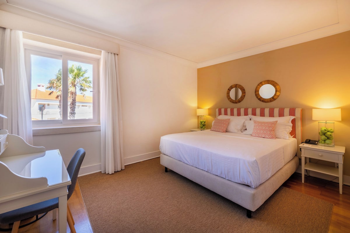 Ein Hotelzimmer mit Bett, Nachttischen, Schreibtisch und Stuhl.