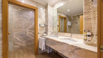 Un baño con paredes de mármol y un espejo grande, un lavamanos y un perchero para toallas.