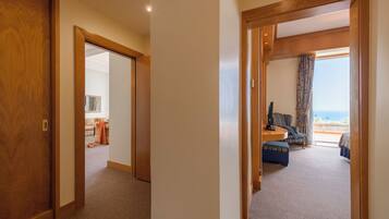 A hotel room with a wooden door, a sofa, a small table, and a view of the outdoors.