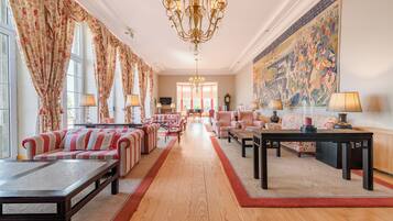 Un'ampia hall d'albergo con divani a righe, un pavimento in legno lungo e un grande murale sulla parete.