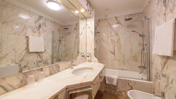 A modern bathroom with a marble sink, a large mirror, a glass-enclosed shower, and a separate bathtub.