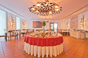 A spacious dining area with a central round table covered in a red tablecloth, surrounded by wooden chairs. - Lam Hotel Convento do Desagravo (Oliveira do Hospital)
