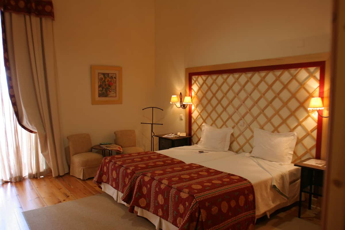 Habitación de hotel con una cama grande, dos mesitas de noche, una silla y un escritorio.