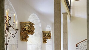 A grand hallway with stone flooring, ornate wall decorations, and a staircase with a wooden handrail. - Lam Hotel Convento do Desagravo (Oliveira do Hospital)