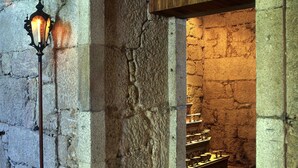 A stone-walled corridor with a wooden door and a lit wall-mounted lamp. - Lam Hotel Convento do Desagravo (Oliveira do Hospital)
