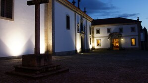 Un edificio histórico con un patio adoquinado, una cruz destacada y una entrada bien iluminada.