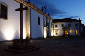 A historic building with a cobblestone courtyard, a prominent cross, and a well-lit entrance. - Lam Hotel Convento do Desagravo (Oliveira do Hospital)