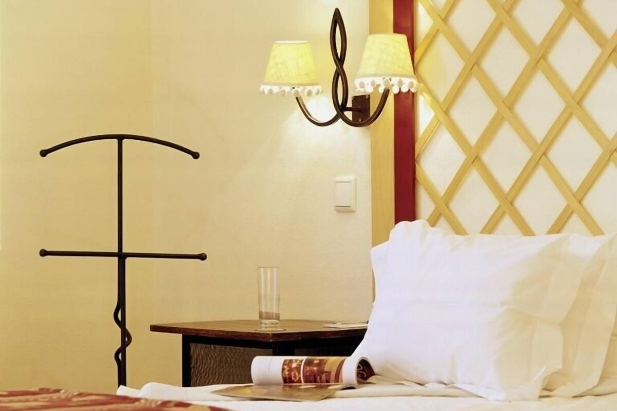 Una habitación de hotel con una cama, una mesita de noche, una lámpara y un panel decorativo en la pared.