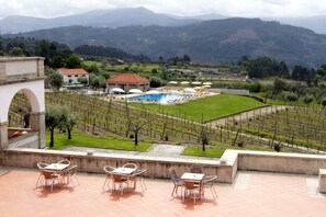 A terrace with outdoor seating and a view of a swimming pool, vineyards, and distant mountains. - Lam Hotel Convento do Desagravo (Oliveira do Hospital)