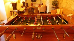 Una mesa de fútbolín en una habitación con un sofá, sillones y una mesa de comedor.