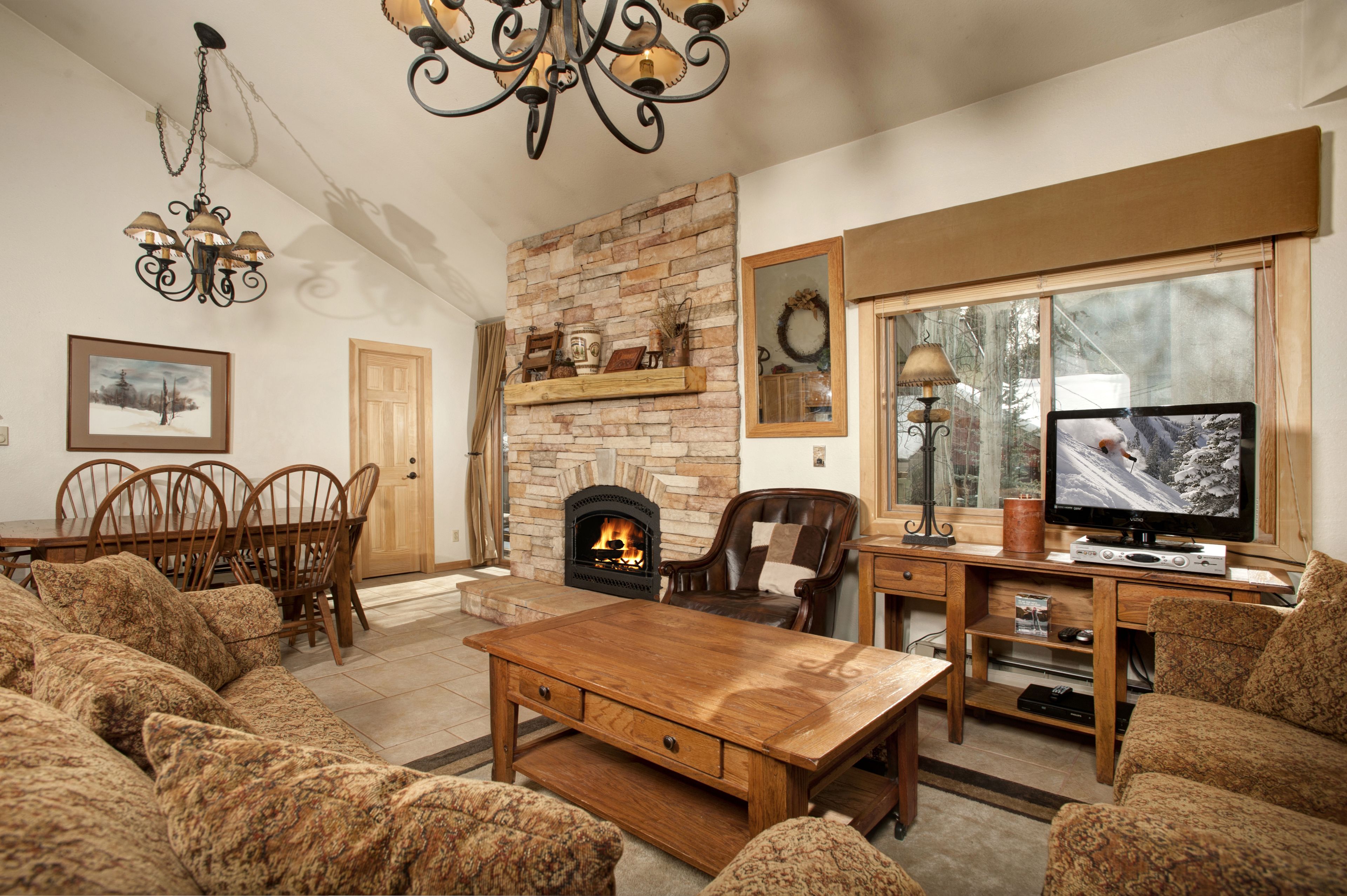 A cozy living room with a fireplace, wooden furniture, and a television.