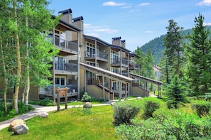 Un edificio a più piani con balconi, una galleria coperta e montagne sullo sfondo.