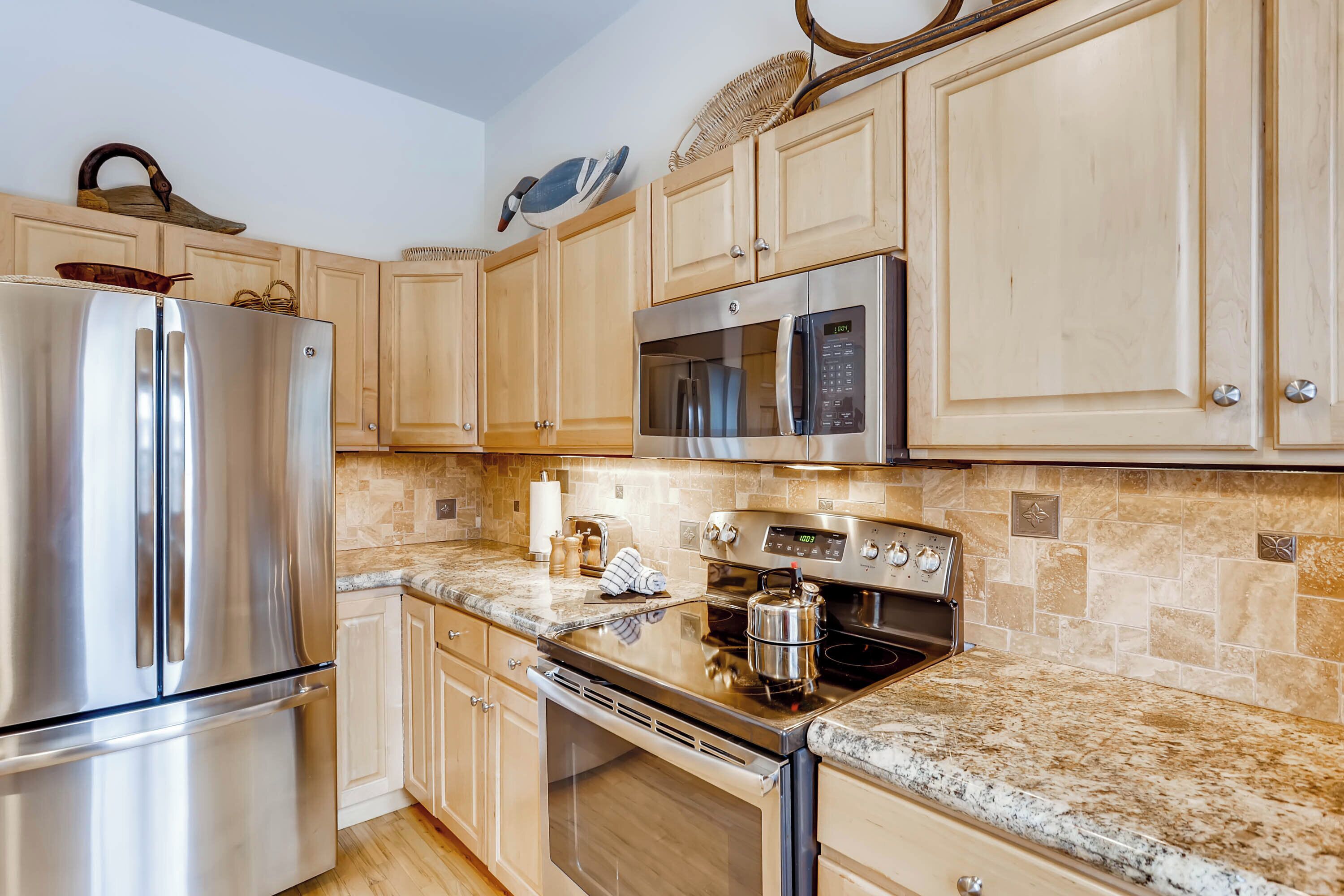 A kitchen with wooden cabinets, stainless steel appliances, a granite countertop, and a backsplash.