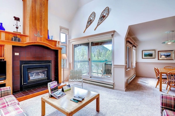 A living room with a fireplace, a balcony with a view, and a dining area. - Forest Condominiums by Vail Resorts (Keystone)