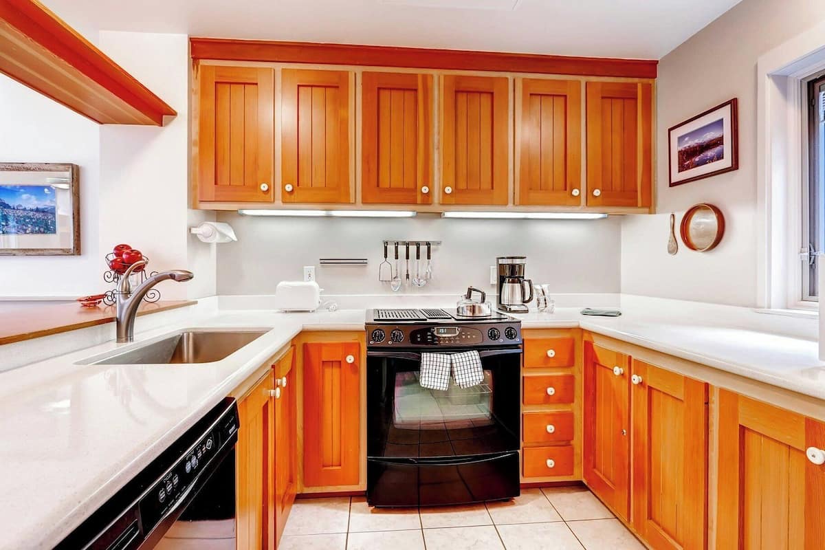 A kitchen with wooden cabinets, a stove, a dishwasher, and a coffee maker.