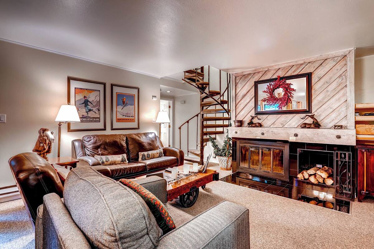 A cozy living room with a fireplace, a staircase, and a dog statue.