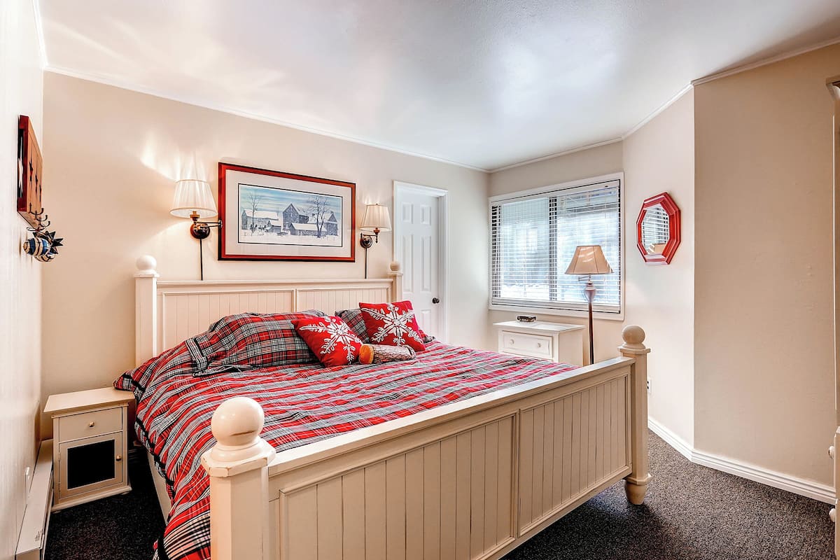A bedroom with a bed, a nightstand, a dresser, a window with blinds, and a framed picture on the wall.