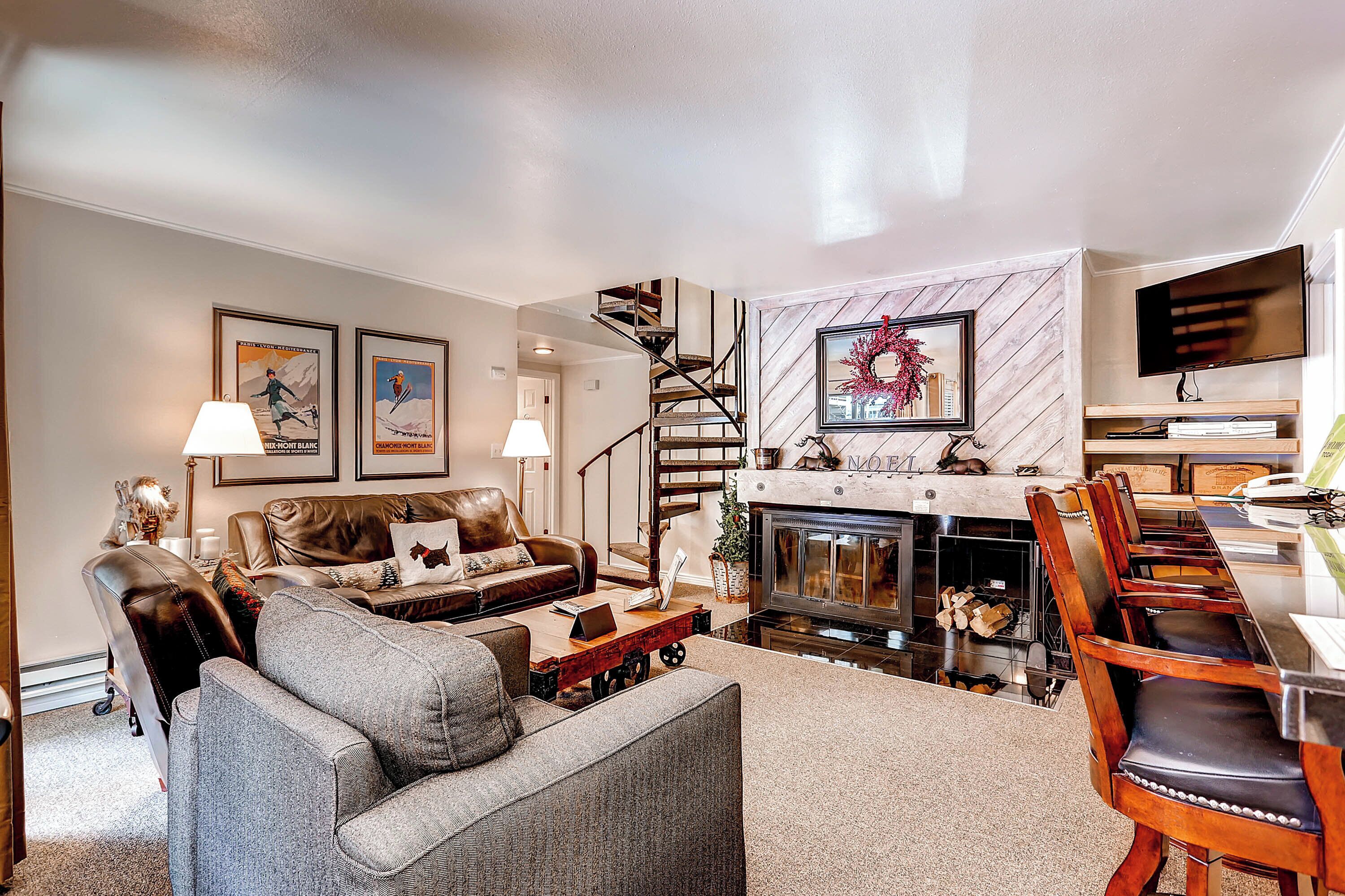 A living room with a fireplace, a staircase, and a TV mounted on the wall.