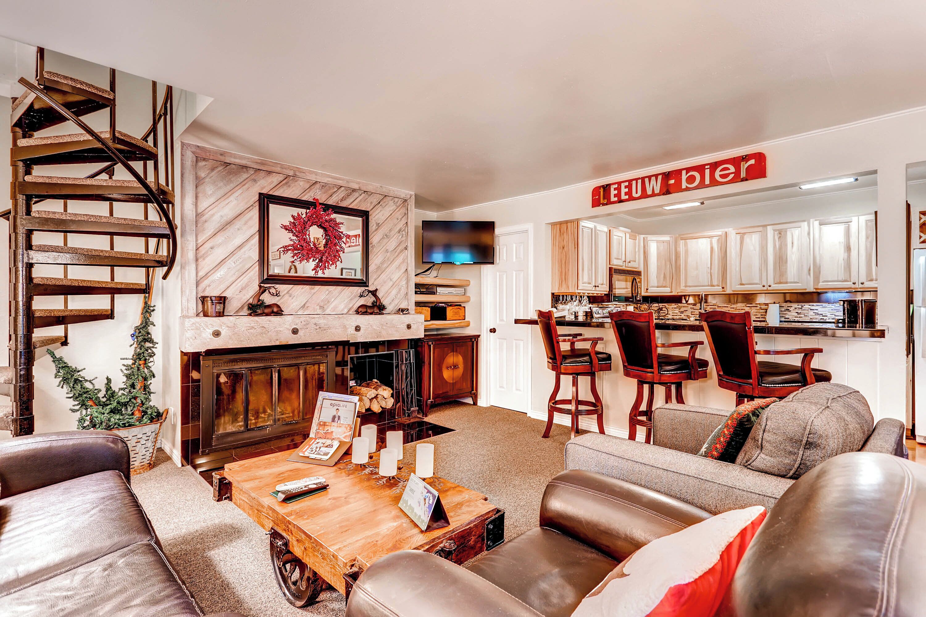 A cozy living room with a fireplace, leather sofas, a wooden coffee table, and a staircase.