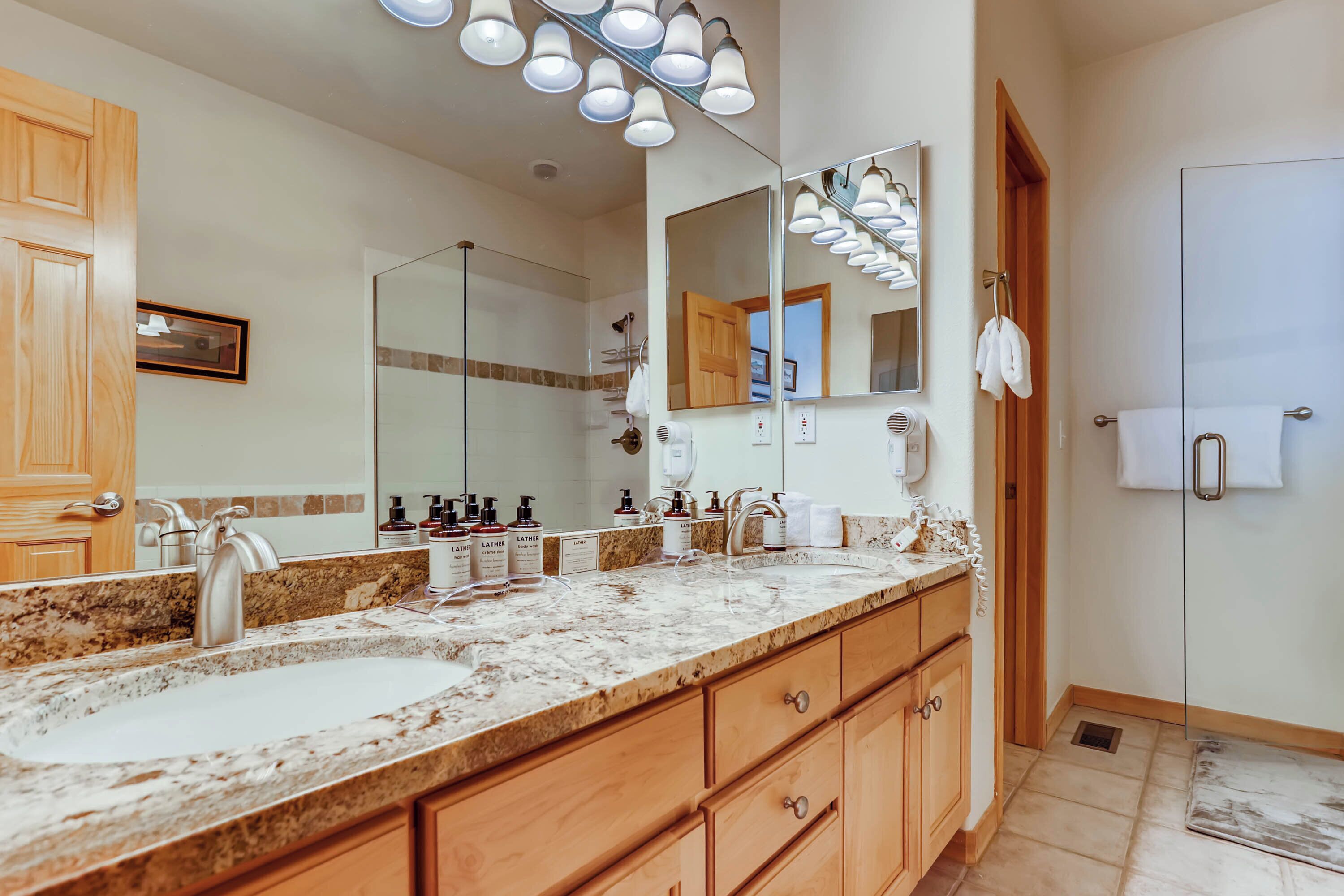A bathroom with two sinks, a large mirror, and a shower area.