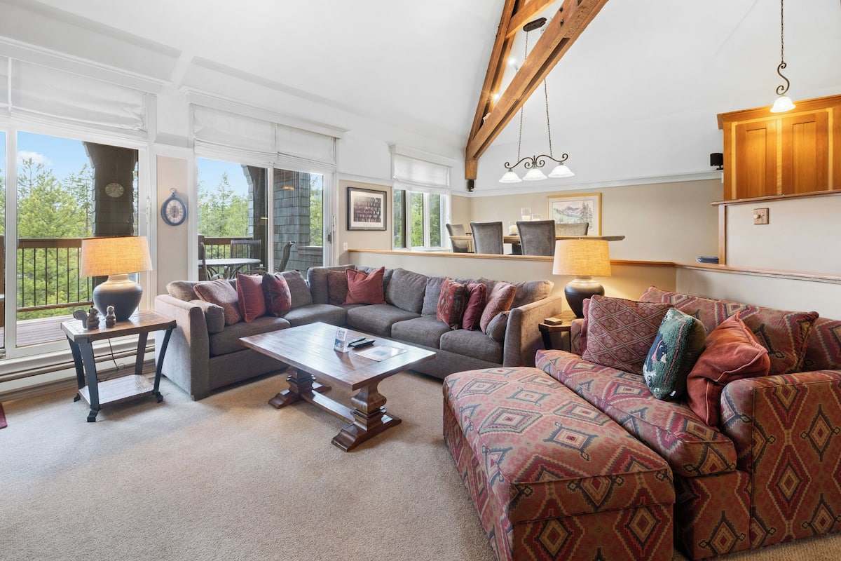 A spacious living room with a large sectional sofa, a coffee table, and a dining area with a table and chairs.