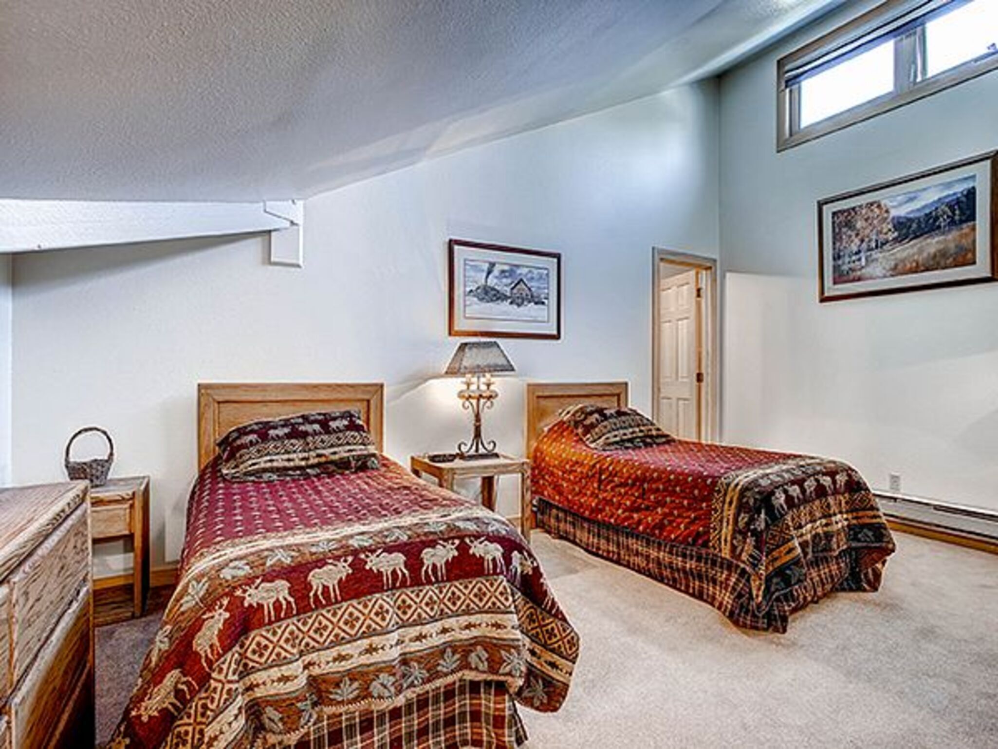 A bedroom with two beds, a nightstand, a lamp, and a framed picture on the wall.
