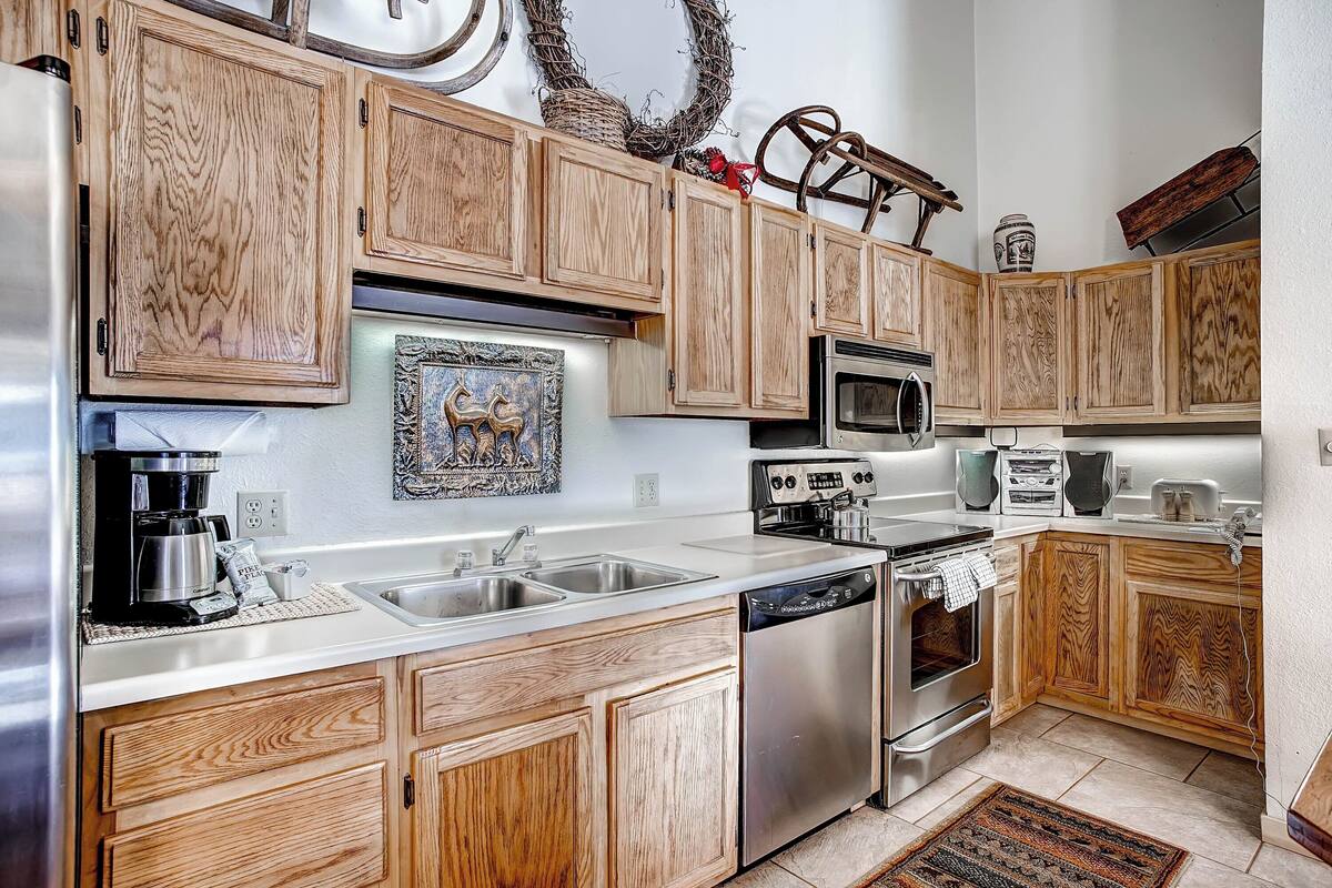 A kitchen with wooden cabinets, stainless steel appliances, and a decorative wall piece.