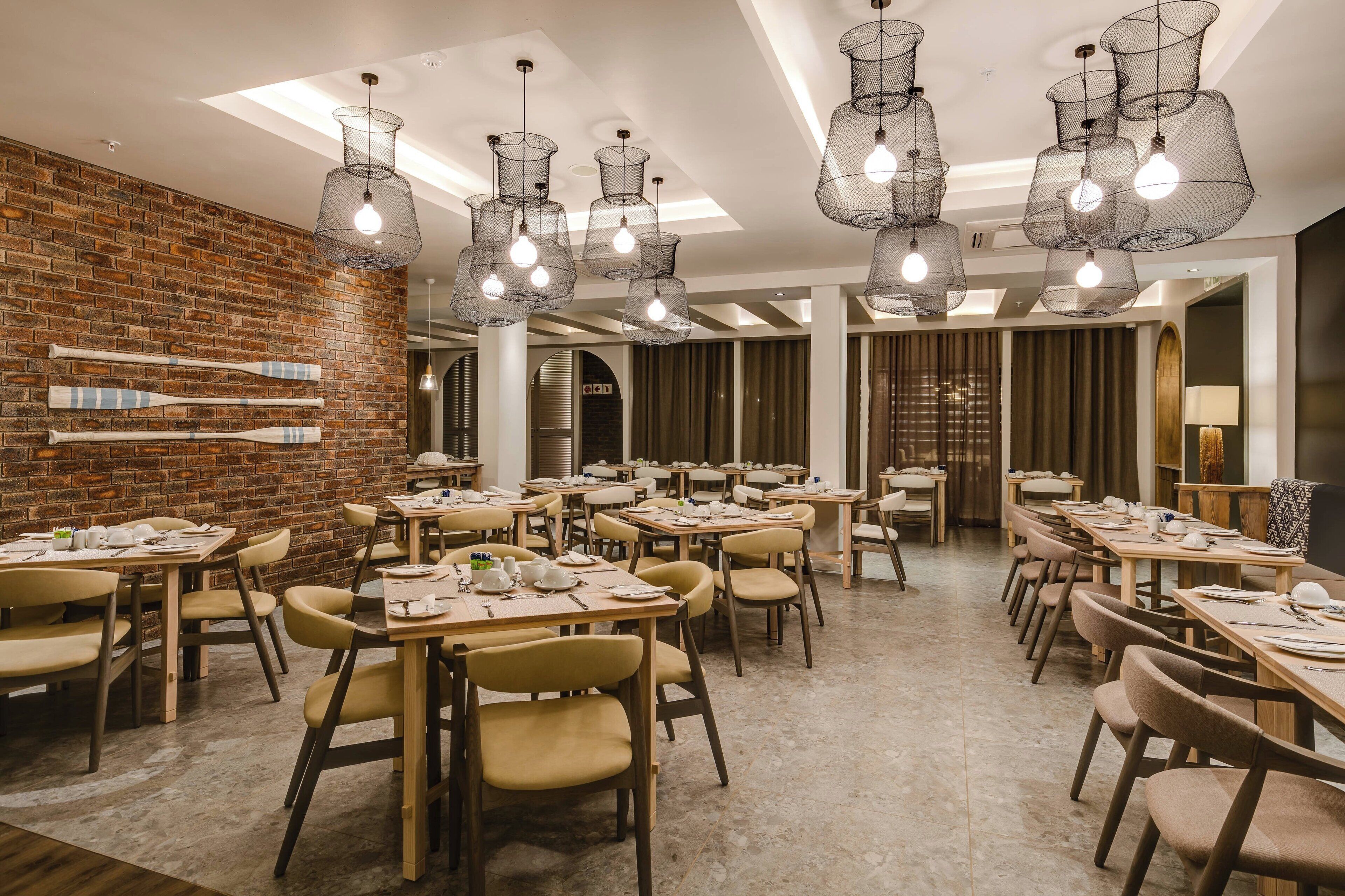 A restaurant with brick walls, multiple tables, and hanging light fixtures.
