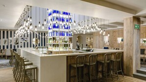 A bar area with a central island, bar stools, hanging light fixtures, and shelves with bottles. - Protea Hotel by Marriott Durban Umhlanga (Umhlanga)