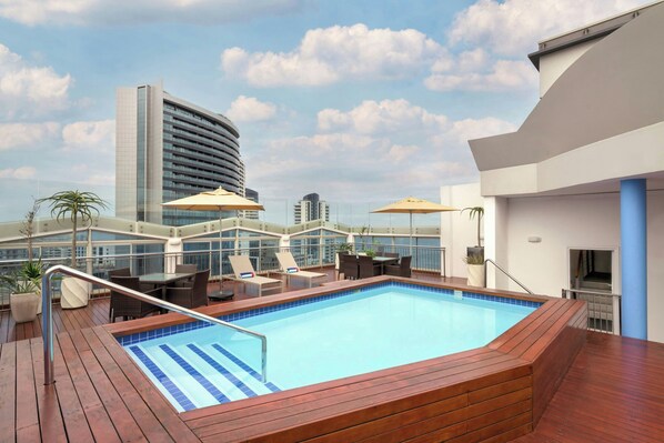 A rooftop pool area with lounge chairs, a swimming pool, and a view of a high-rise building. - Protea Hotel by Marriott Durban Umhlanga (Umhlanga)