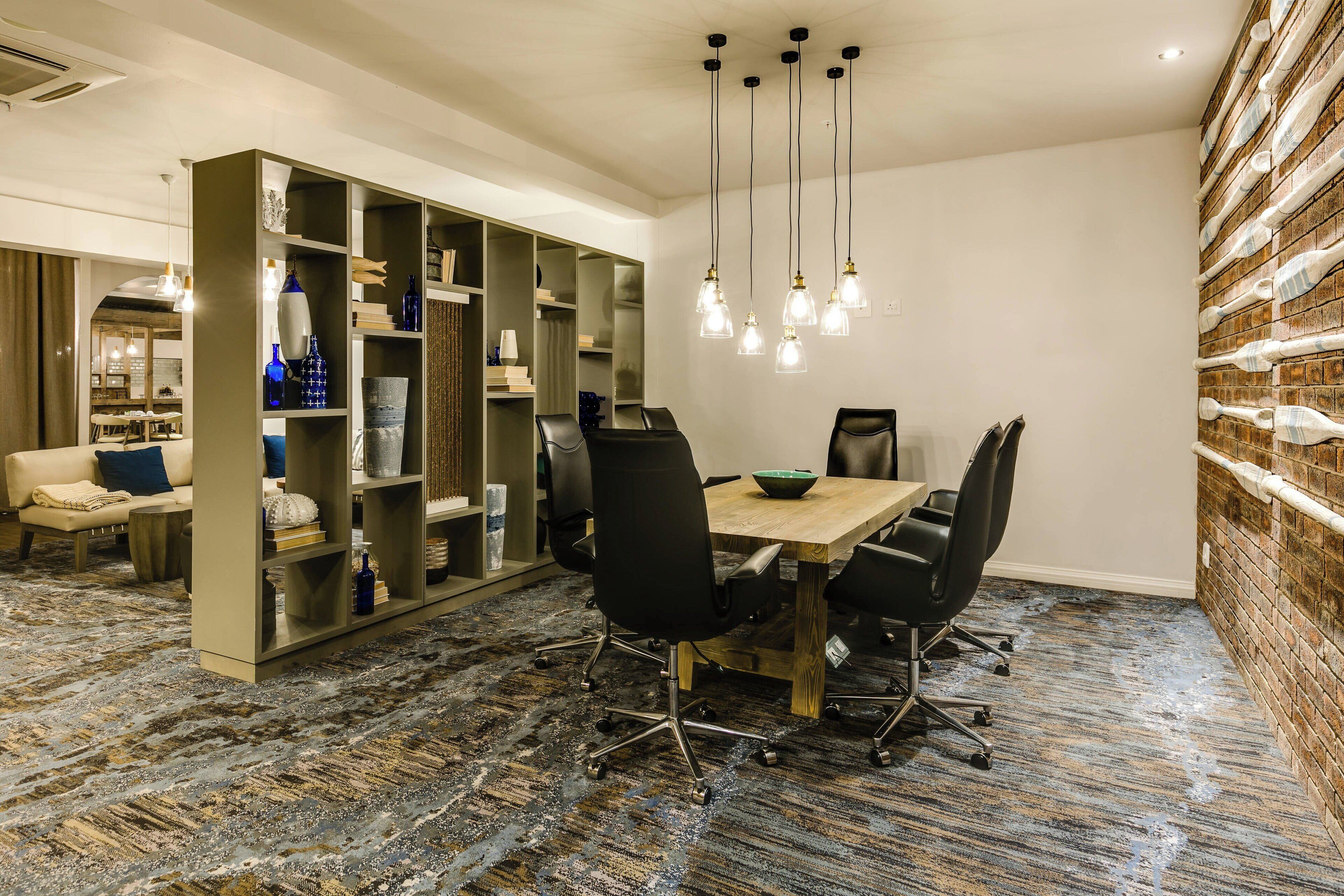 A conference room with a large table, black chairs, and a bookshelf.
