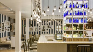 A bar area with a long counter, hanging light fixtures, and shelves of blue bottles. - Protea Hotel by Marriott Durban Umhlanga (Umhlanga)
