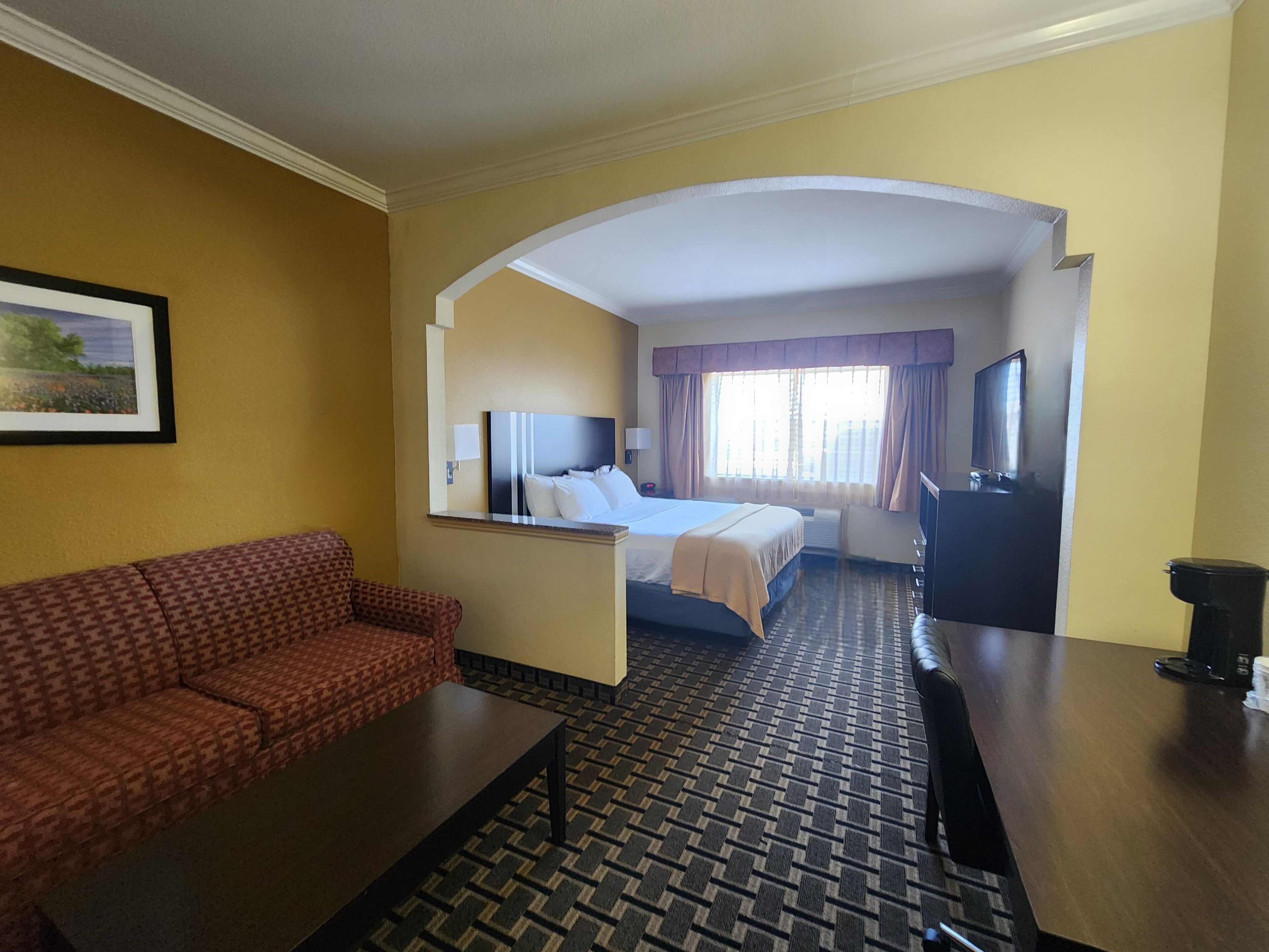 Une chambre d’hôtel équipée d’un canapé, d’un lit, d’un bureau et d’une télévision.