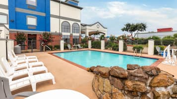 Een buitenzwembad en ligstoelen