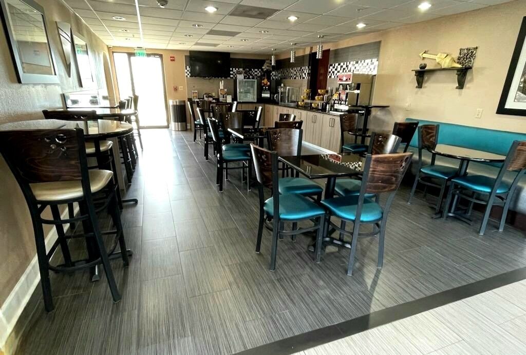 Un restaurante con cabinas y mesas, una zona de cocina y una barra.