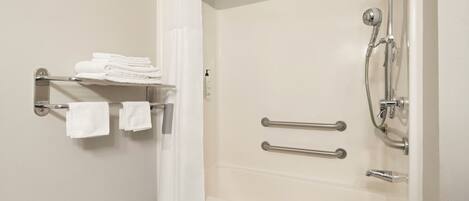 A bathroom with a bathtub, a shower, and a towel rack with folded towels.
