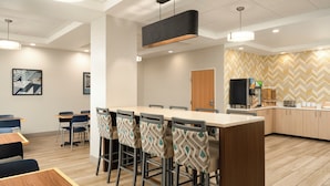 A modern kitchen with a central island, bar stools, and a coffee machine.