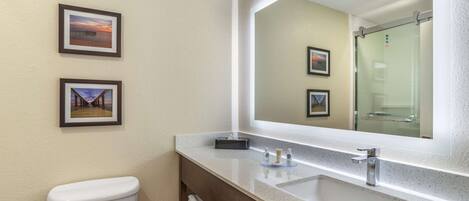 A bathroom with a toilet, a sink, a mirror, and two framed pictures on the wall.