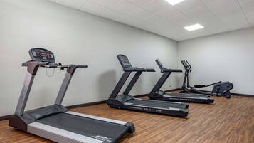 Ein Fitnessraum mit drei Laufbändern, einem Crosstrainer und einem stationären Fahrrad.