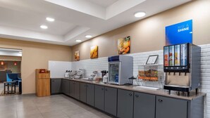 A modern kitchen area with a coffee machine, a juice dispenser, and a refrigerator. - Comfort Inn & Suites Millbrook - Prattville (Millbrook)